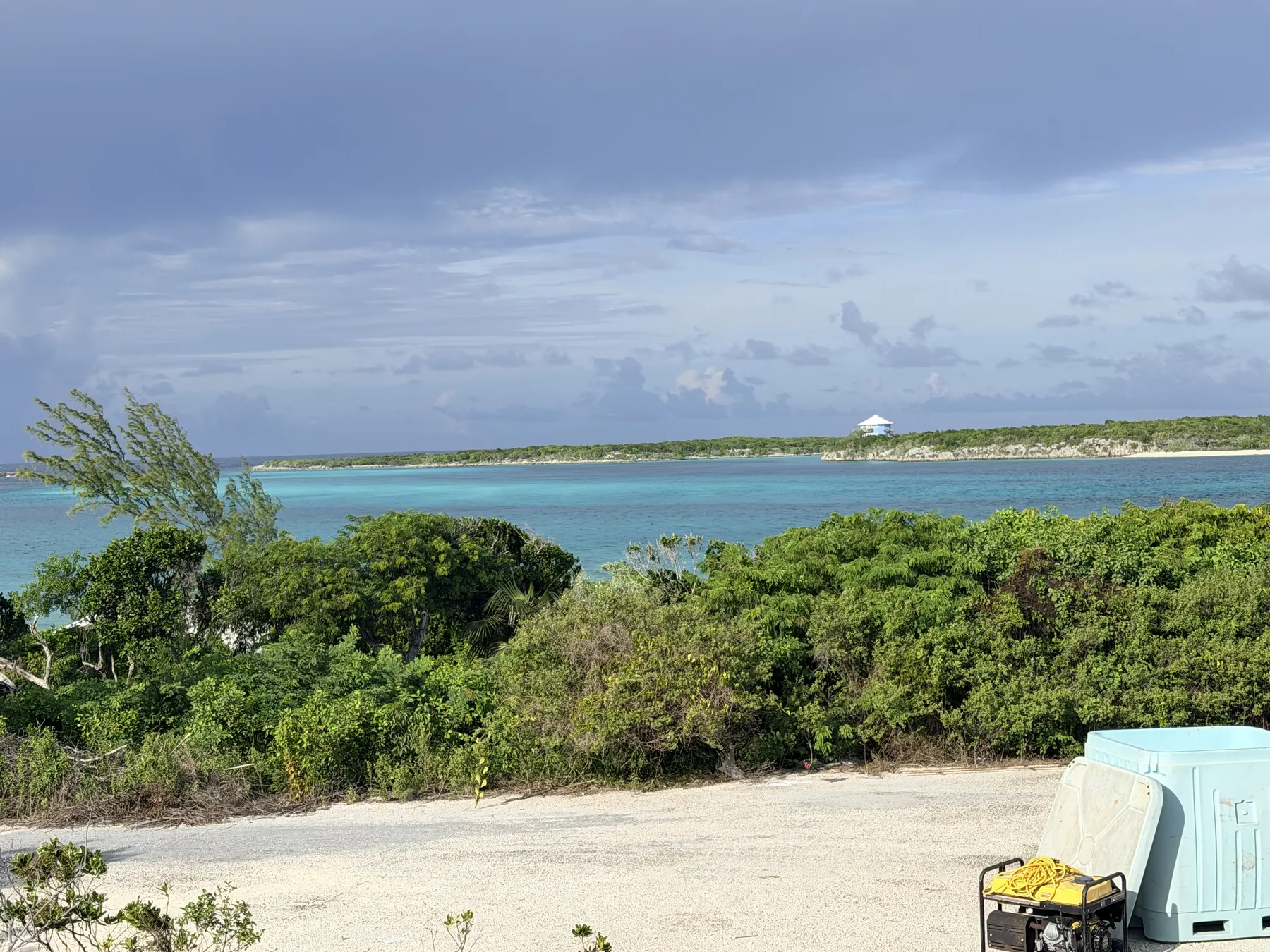 Turquoise water and low green cays beyond a sandy clearing