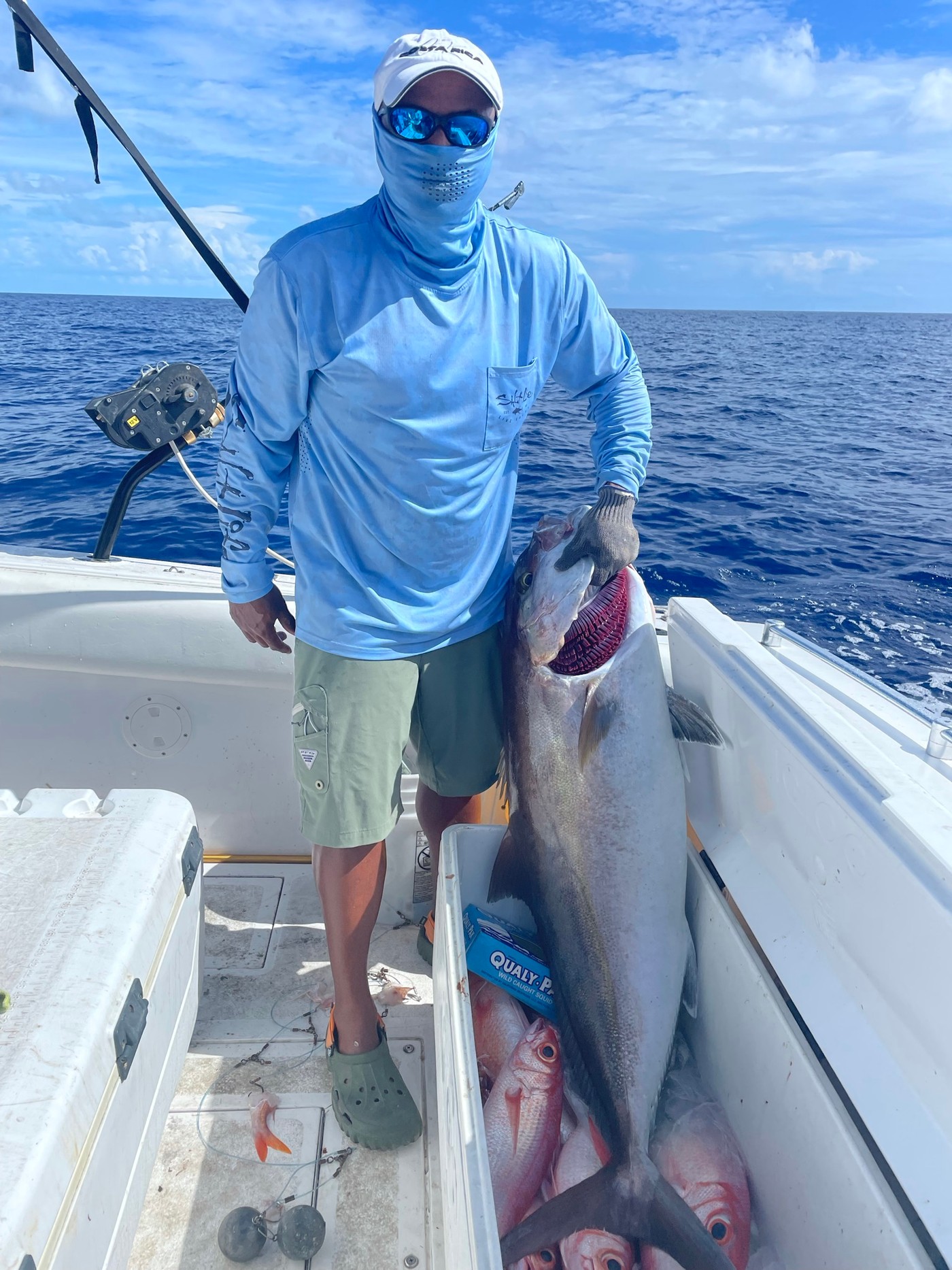 Angler holding a large catch aboard a boat on open water
