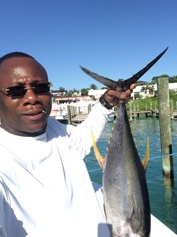 Ty holding a catch beside the water at a marina