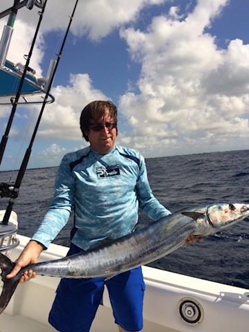 Angler holding a long catch aboard a boat at sea